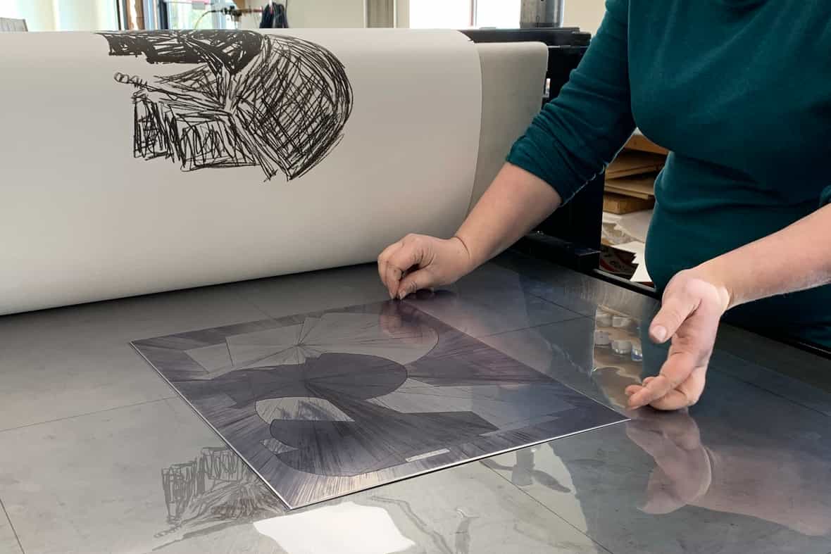 Close up of a woman preparing an intaglio plate on an etching press.