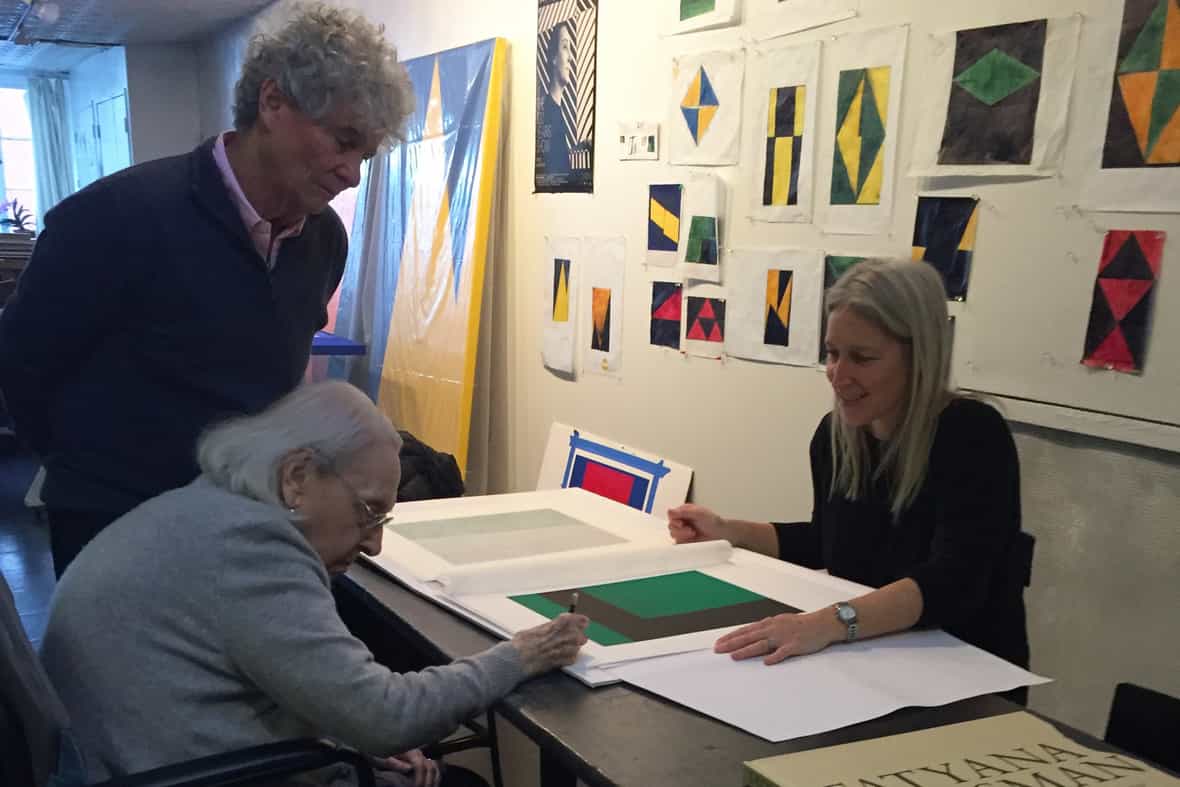 Carmen Herrera signing the edition with assistant Tony Bechera and ULAE director Larissa Goldston.