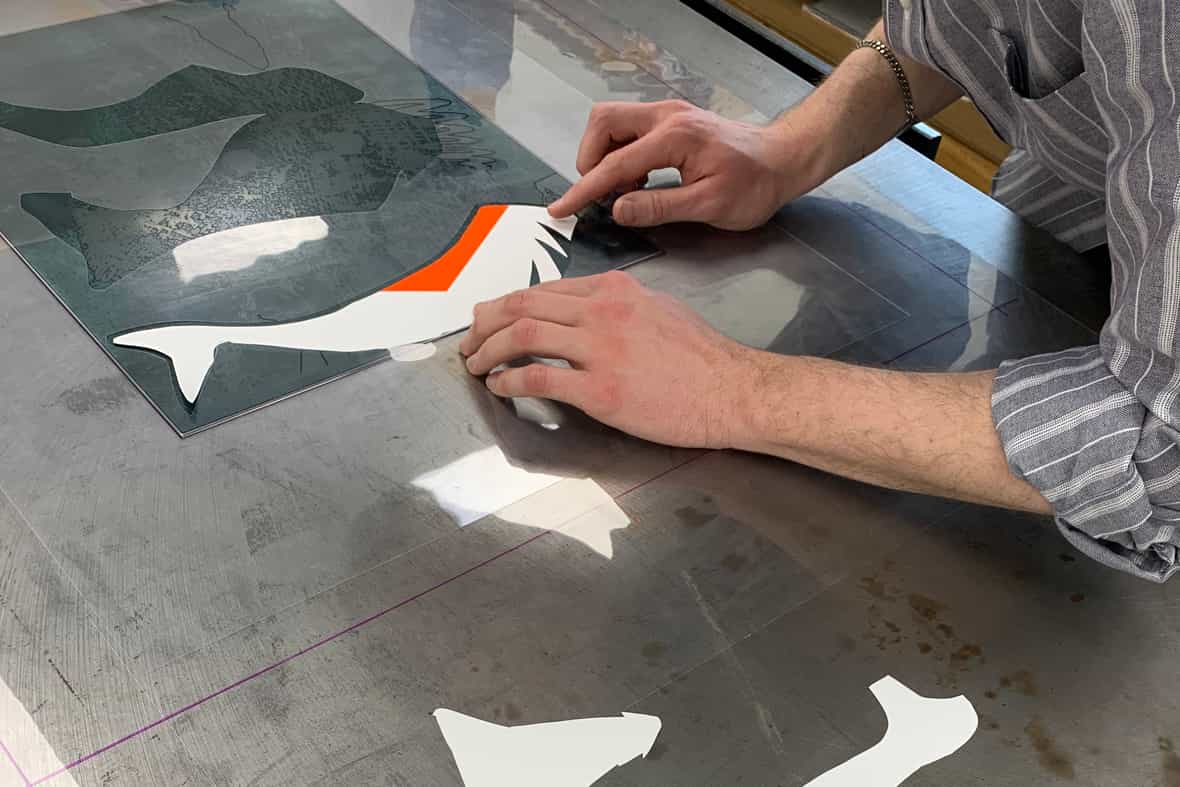 Printer Michael Rahn adjusting the inked mask laid on an etching plate.