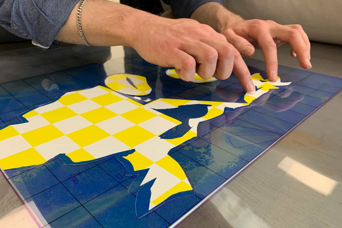 Printer Michael Rahn adjusting the inked mask laid on an etching plate.